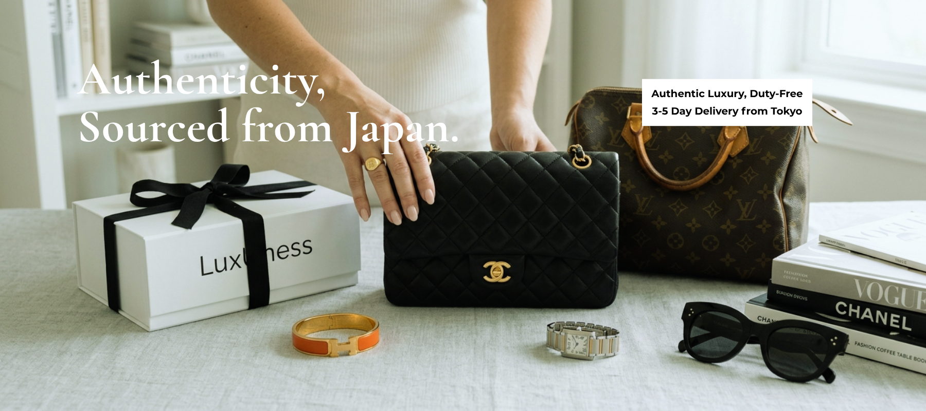 Black Chanel handbag on a table with luxury items and branding text.